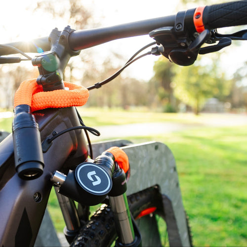 Chaîne antivol Serea Swift orange attachée à un vélo électrique sur un arceau