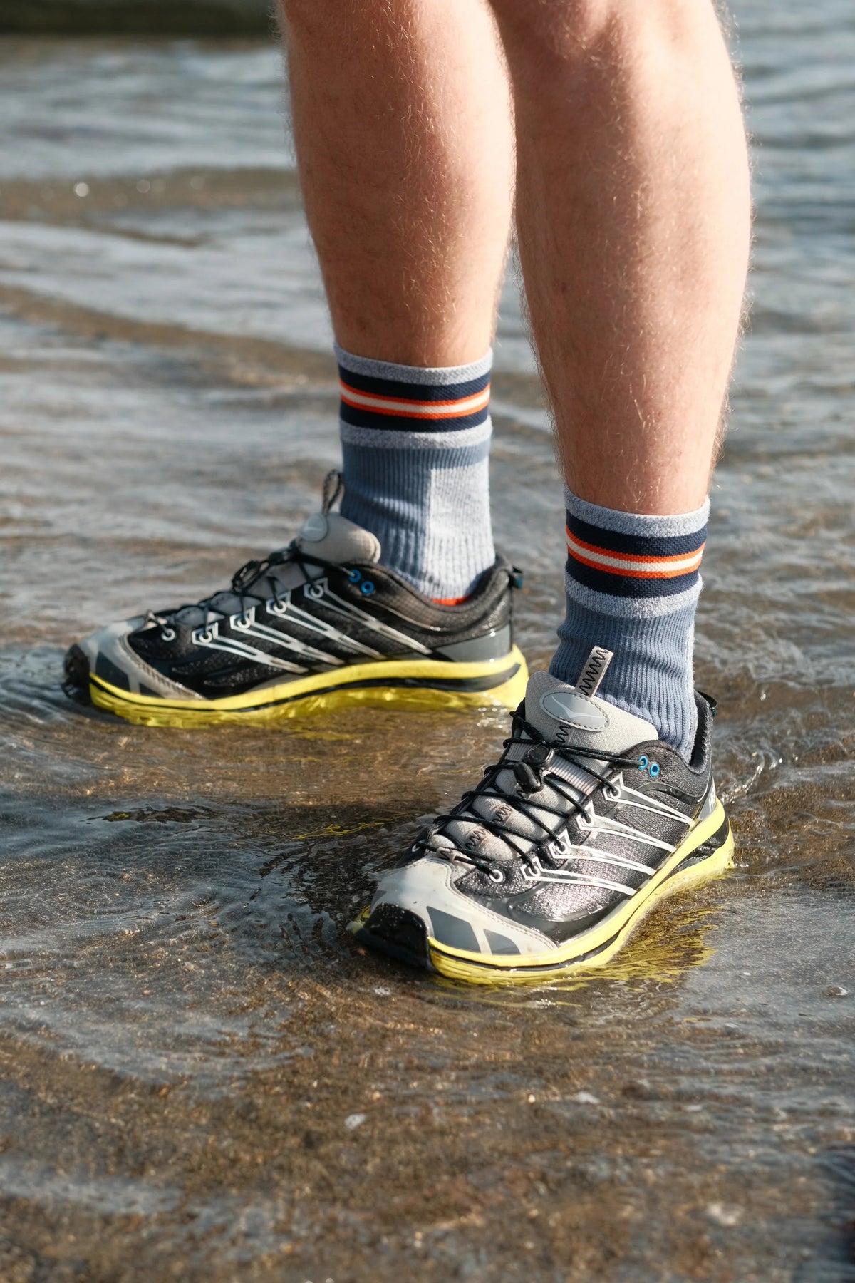 Chaussettes imperméables Sealskinz rayées portées avec des baskets dans l'eau