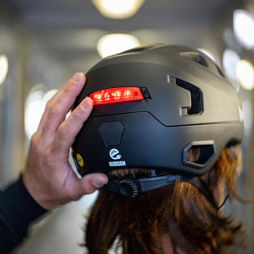 Éclairage arrière Bern Click-Mount allumé sur un casque vélo Bern Hudson en ville