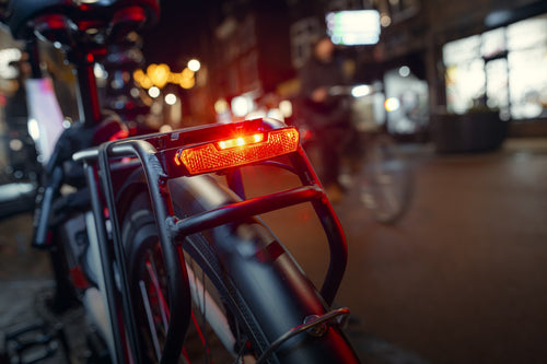 Feu arrière AXA Juno allumé sur un porte-bagage, vélo en ville la nuit