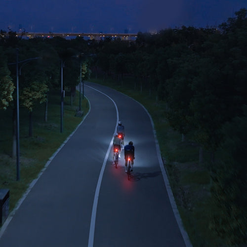 Cyclistes équipés du feu arrière iGPSPORT ET6 sur une piste cyclable au crépuscule