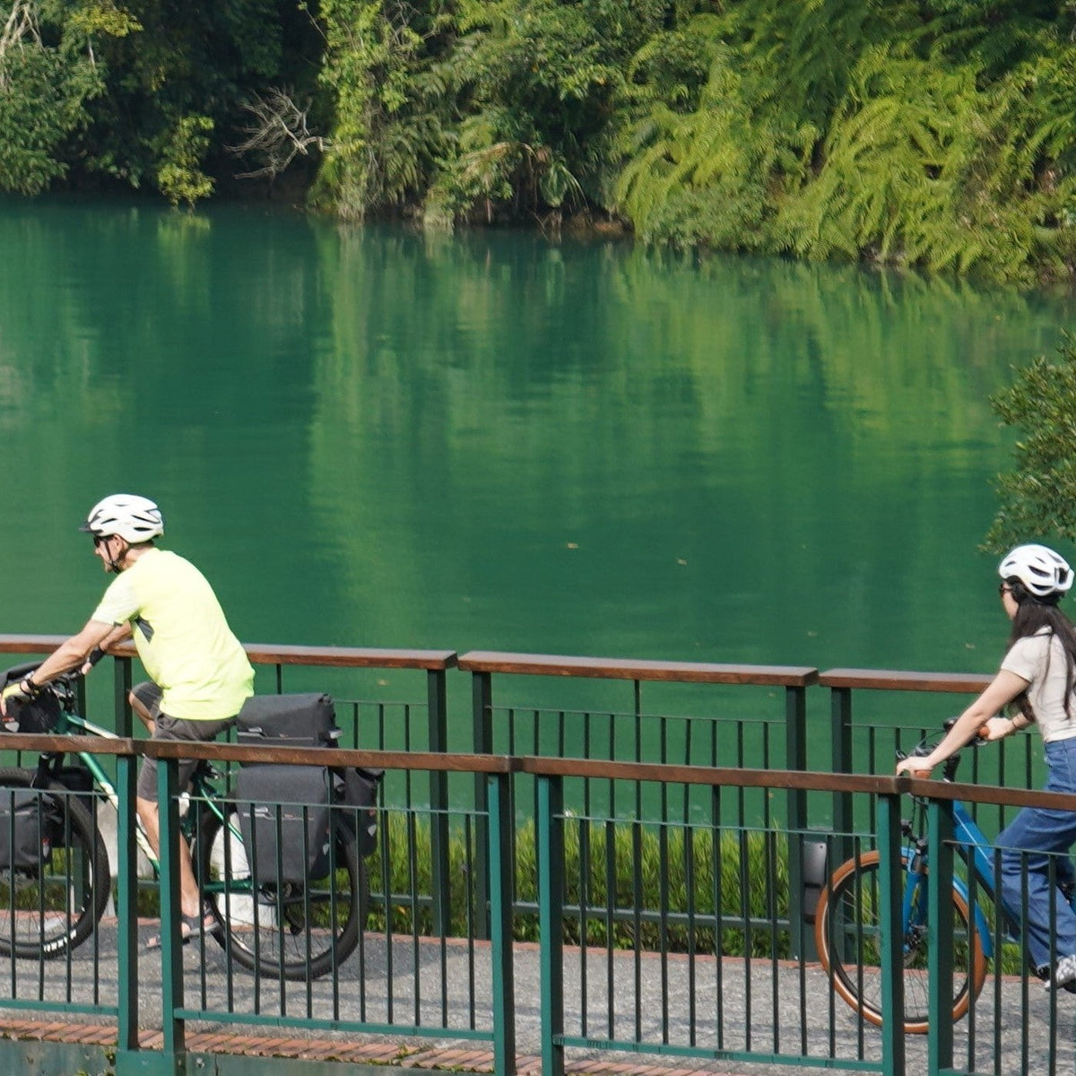 Deux cyclistes équipés de sacoches Ibera sur une passerelle au bord d'un lac