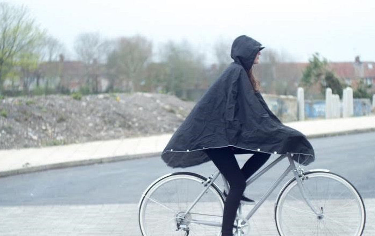 Cycliste en poncho The People's Poncho noir à vélo sous la pluie