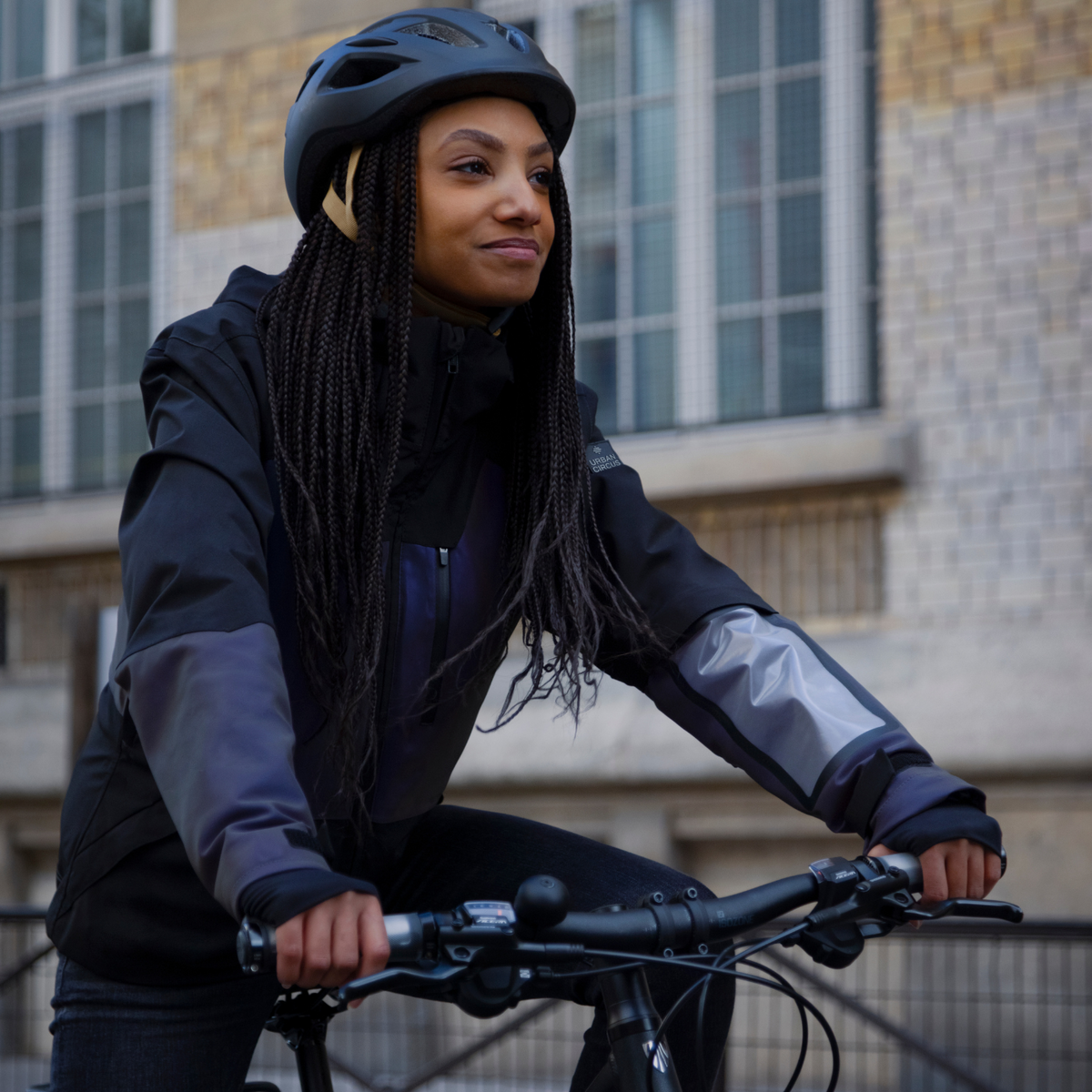 Cycliste Urban Circus à vélo en ville avec veste de pluie et casque