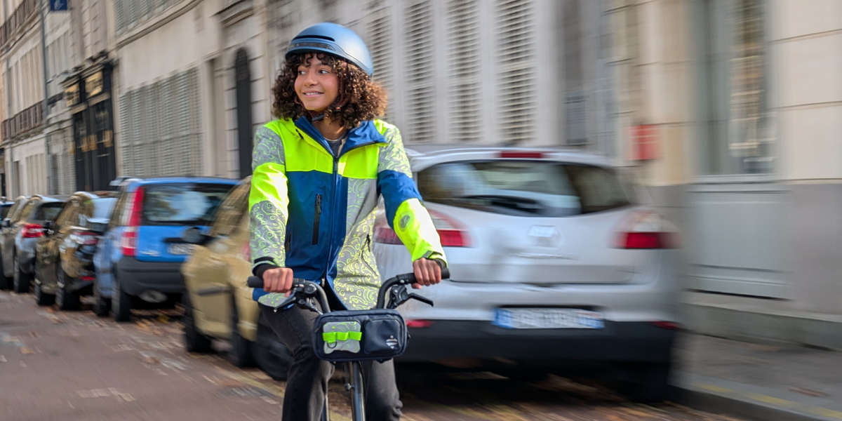 Cycliste en veste réfléchissante Urban Circus REPOP à vélo en ville