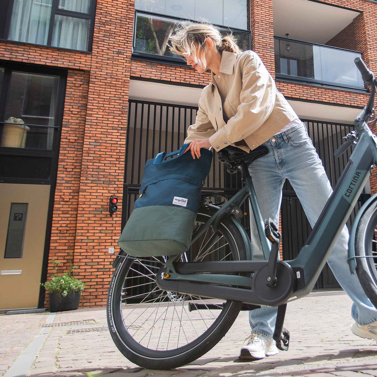 Sacoche Urban Proof Shopper bleue accrochée à un vélo en ville